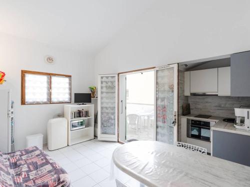 une cuisine avec des armoires blanches et une table dans une pièce dans l'établissement Chaleureuse Villa à Gruissan - 6 pers, Près de la Plage, Garage, Cuisine Équipée, Confort Moderne - FR-1-409A-17, à Gruissan