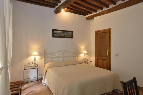 um quarto com uma cama branca e 2 candeeiros em Il Palazzetto em Montepulciano