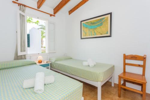 a bedroom with two beds and a chair at Son Xoriguer 6 in Son Xoriguer