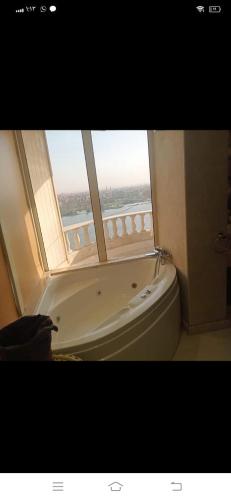 een badkamer met een bad en een raam bij شقه سكنيه in Caïro