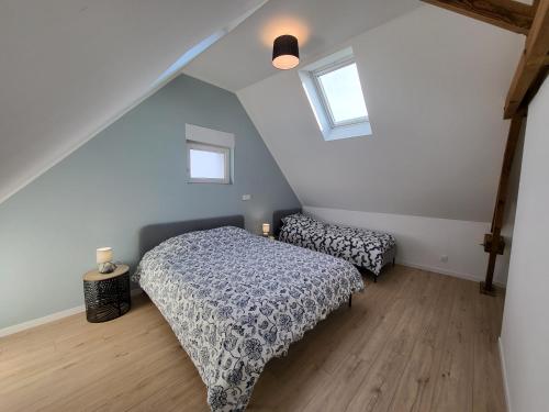 een slaapkamer op zolder met een bed en 2 ramen bij La maison des vacances 8 personnes in Ghyvelde