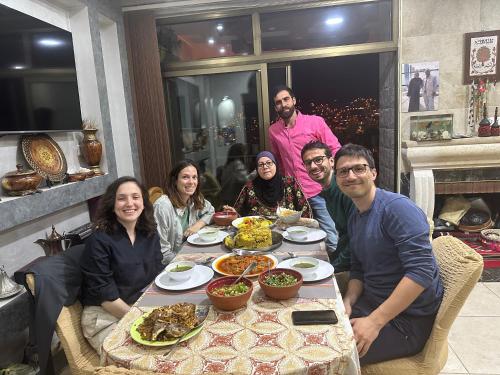 a group of people sitting around a table with food at Petra View Flat in Wadi Musa