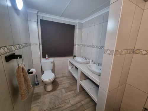 ein Badezimmer mit einem WC, einem Waschbecken und einem Spiegel in der Unterkunft Hoep Hoep Self Catering in Groblersdal