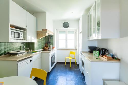 cocina con armarios blancos, mesa y sillas amarillas en Ambassador River View Suites, en Lisboa