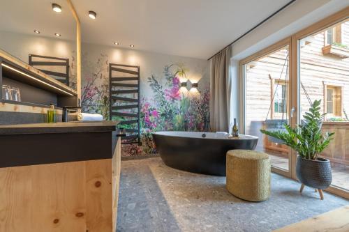 a bathroom with a large tub and a large window at Ferienhotel Jörglerhof in Hainzenberg
