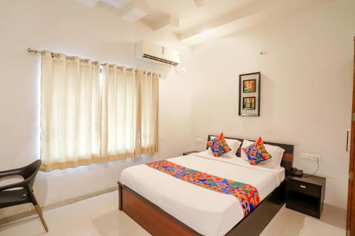 a bedroom with a bed and a chair and a window at FabHotel Archanil Apartment in Nagpur