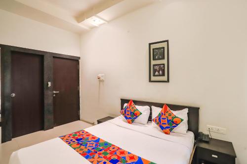 a bedroom with a bed with colorful pillows on it at FabHotel Archanil Apartment - Sitanagar Cricket Ground in Nagpur
