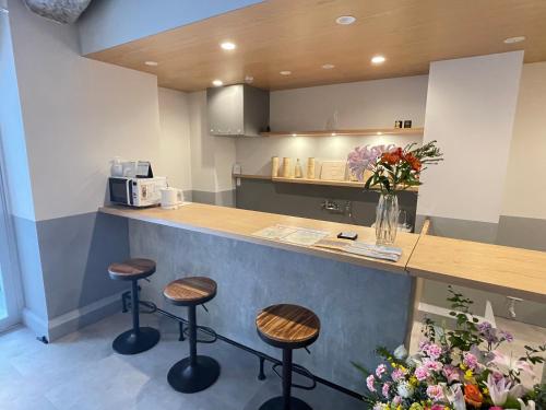 a kitchen with three stools at a counter at Hotel Apreton in Tokyo