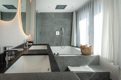 a bathroom with a sink and a bath tub at Hotel Steffani in St. Moritz