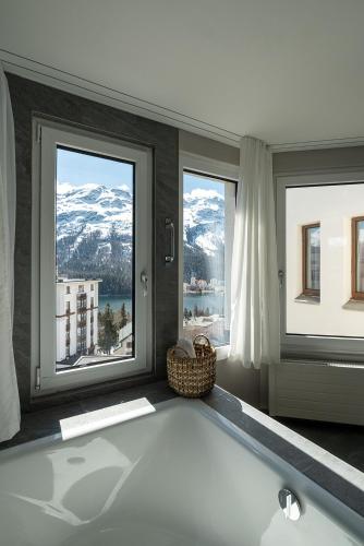 a bathroom with a bath tub in front of windows at Hotel Steffani in St. Moritz