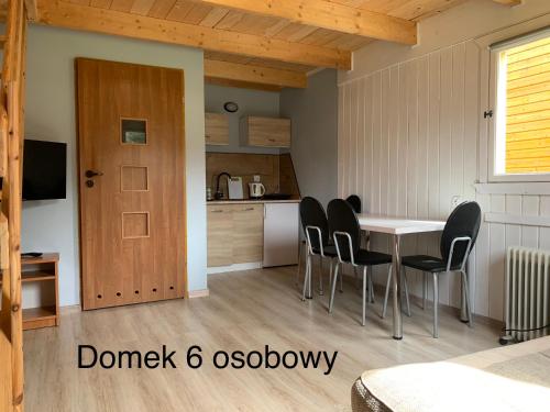 een keuken en eetkamer met een tafel en stoelen bij Domki Pod Lasem in Mrzeżyno