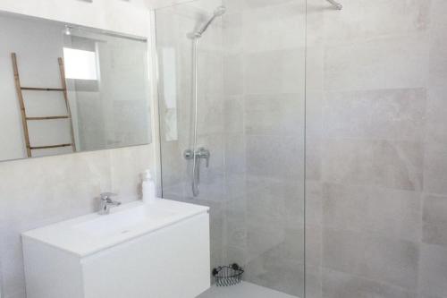 een witte badkamer met een douche en een wastafel bij Terrazas Faro 18 in El Pozo de los Frailes