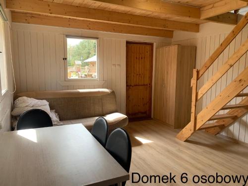 Habitación con mesa, sofá y escalera. en Domki Pod Lasem en Mrzeżyno