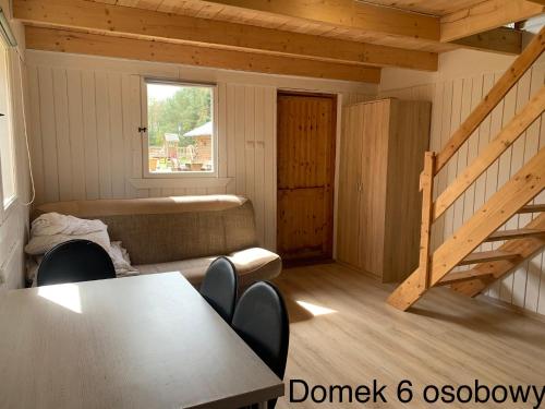 a room with a table and a couch and a staircase at Domki Pod Lasem in Mrzeżyno