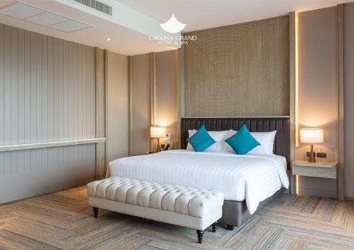 a bedroom with a large white bed with blue pillows at Laguna Grand Hotel & Spa Songkhla in Songkhla
