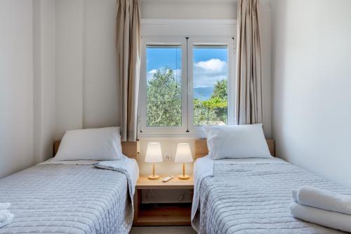 two beds in a small room with a window at Lyrids Apartments in Episkopí- Rethimno