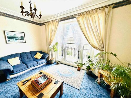 uma sala de estar com um sofá azul e uma mesa em Perfect for large groups! em Torquay