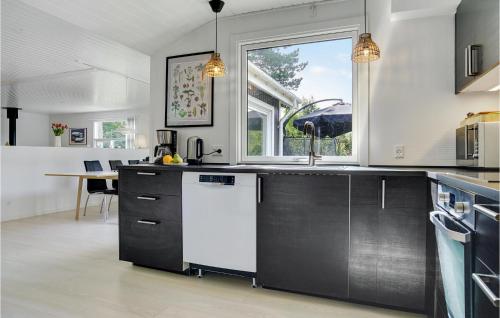 a kitchen with black cabinets and a white dishwasher at Amazing Home In Væggerløse With Sauna in Marielyst
