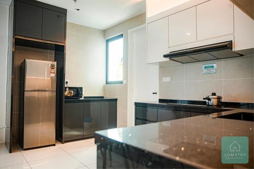 a kitchen with a stainless steel refrigerator and black counter tops at JOMSTAY Sunway Onsen Suites Ipoh - Lost World of Tambun Ipoh Waterpark in Tambun