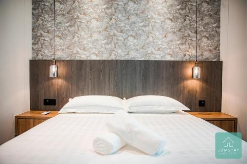 a bedroom with a white bed with two towels on it at JOMSTAY Sunway Onsen Suites Ipoh - Lost World of Tambun Ipoh Waterpark in Tambun