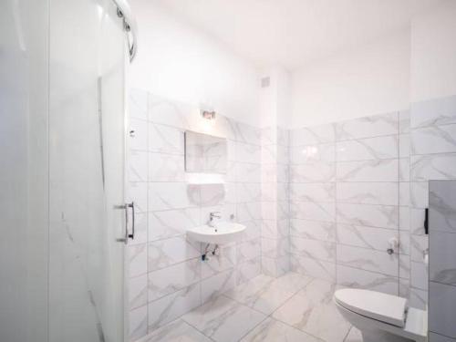 a white bathroom with a toilet and a sink at Apartamenty pod Jagodną in Spalona