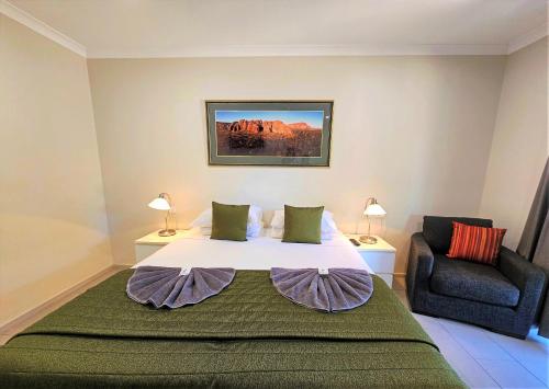 um quarto com uma cama grande e uma cadeira em Lily Lagoon Resort em Kununurra