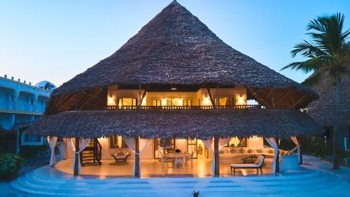 un resort con un grande edificio di paglia con piscina di Alawi Home a Watamu