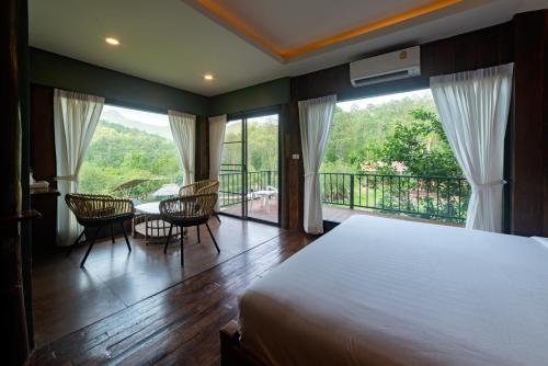 a bedroom with a bed and a balcony with a table and chairs at Tawan Riverside in Mae Wang