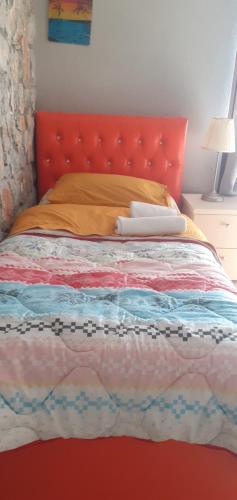 a bed with an orange headboard and a red bedspread at Hotel Villa Stone Dream Bar Restaurant in Pogradec