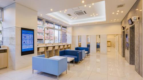 a lobby of a building with blue chairs and tables at Toyoko Inn Kasukabe-eki Nishi-guchi in Kasukabe