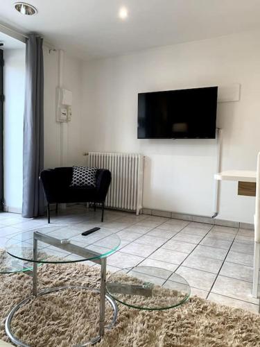 a living room with a glass table and a tv at Appartement cosy Lons - Montmorot in Montmorot