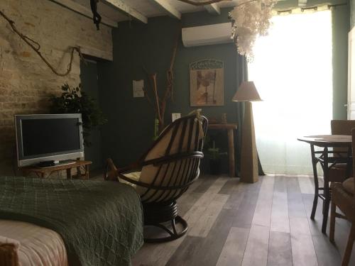 a bedroom with a rocking chair and a television at Au Domaine du Petit Cercoux in Saint-Saturnin-du-Bois