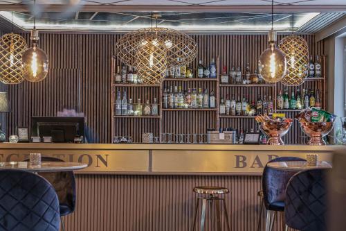 a bar with a counter and some chairs and lights at Hotell Arkad in Västerås
