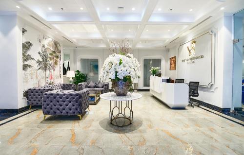 a lobby with couches and a vase of flowers on a table at The Yen Residences Halong in Ha Long