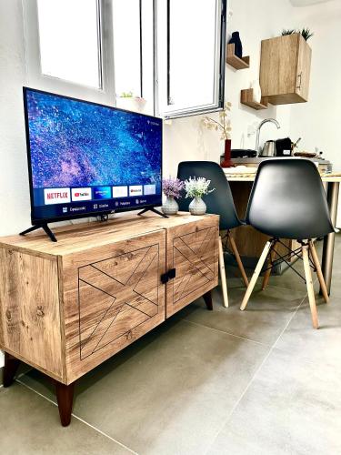a television on a wooden stand with two chairs and a desk at Aeron Suites in Éxo Goniá