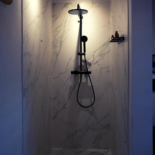 a bathroom with a light fixture on a marble wall at Les Monts d'Aisne in Mormont