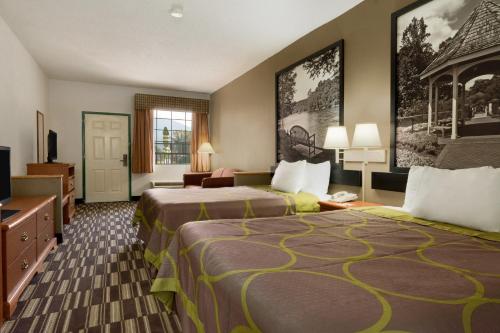 a hotel room with two beds and a television at Super 8 by Wyndham Chatsworth/Dalton in Chatsworth