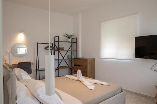 a white room with a bed and a television at Aegean Eyes 3bd House Βy the Sea in Kefalos
