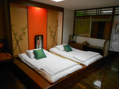 two beds in a room with white sheets and green pillows at B.S. Court Hotel Sathorn in Bangkok