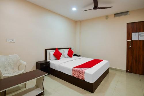 Un dormitorio con una cama con almohadas rojas y una silla en Flagship 85554 Hotel Premium Hari en Jamshedpur