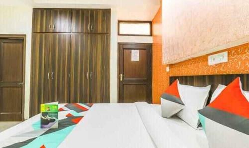 a bedroom with a large white bed with colorful pillows at FabExpress Mayank Palace in Chandīgarh