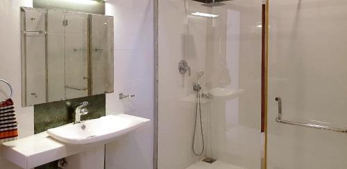 a white bathroom with a sink and a shower at Hotel Coconut Bar Sea Lodge in Beruwala