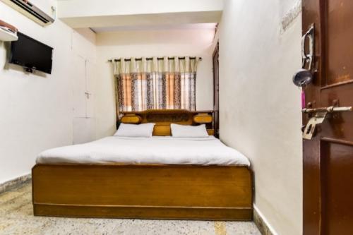 um pequeno quarto com uma cama e uma janela em OYO Krishna Athithi Bhawan em Moradabad
