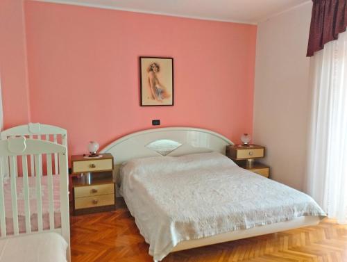 una camera da letto con pareti rosa, un letto e una culla di Apartment Danica 356 a Umag (Umago)