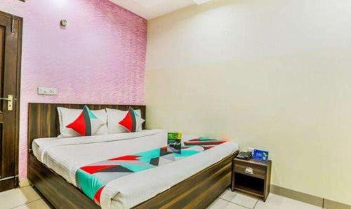 a bedroom with a bed and a pink wall at FabExpress Mayank Palace in Chandīgarh