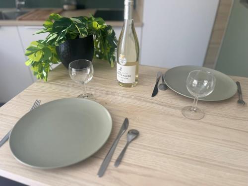 a table with plates and glasses and a bottle of wine at Le Duplex studio centre de Nîmes avec Clim in Nîmes