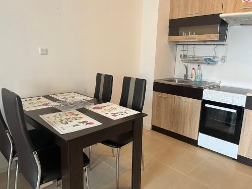 uma cozinha com uma mesa com cadeiras e um fogão em Green Life Beach Resort Paradise Apartment em Sozopol