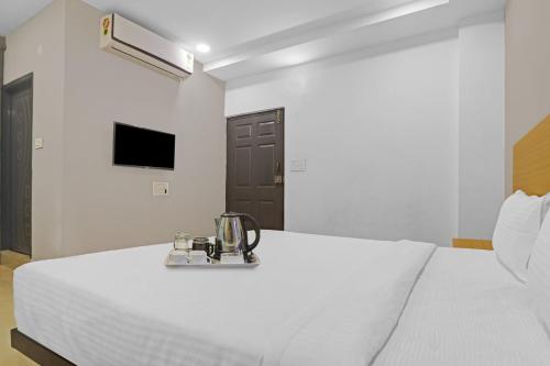 ein weißes Schlafzimmer mit einem Bett mit einem silbernen Gerät darauf in der Unterkunft Super Townhouse 862 Che Sigma in Hyderabad
