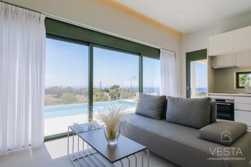 a living room with a couch and a large window at Olive Grove Suites - Villas with private pool and garden in Nikiti
