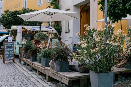 une table avec des plantes en pot et un parapluie dans une rue dans l'établissement Hotel Fletzinger, à Wasserburg am Inn